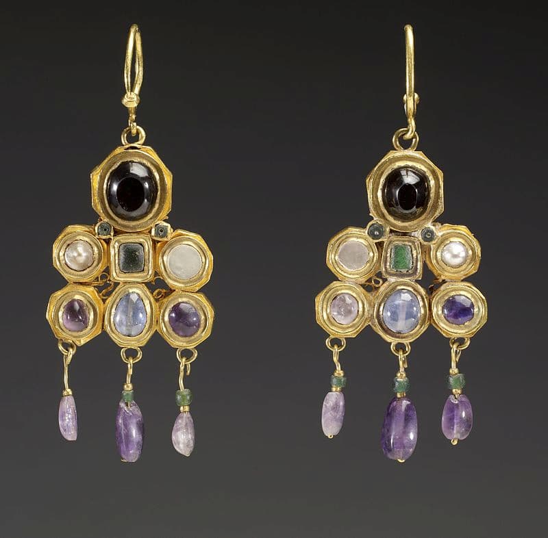 An image of medieval earrings with 10 gemstones each of differing colors, detailed metalwork, and hanging baubles.